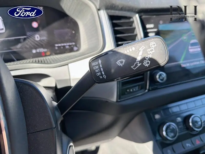 Levier de commande des essuie-glaces en gros plan dans l'habitacle d'un SKODA KODIAQ noir Magic Nacré, vue côté conducteur.