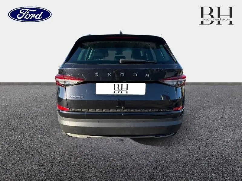 Vue arrière d'un Skoda Kodiaq noir Magic Nacré 2023 avec feux arrière LED et hayon fermé sur sol gris.