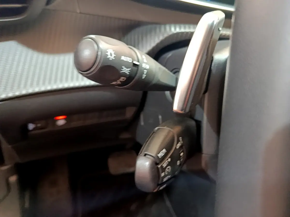Gros plan sur les commandes de clignotants et essuie-glaces du Peugeot 2008 gris clair côté gauche du volant.