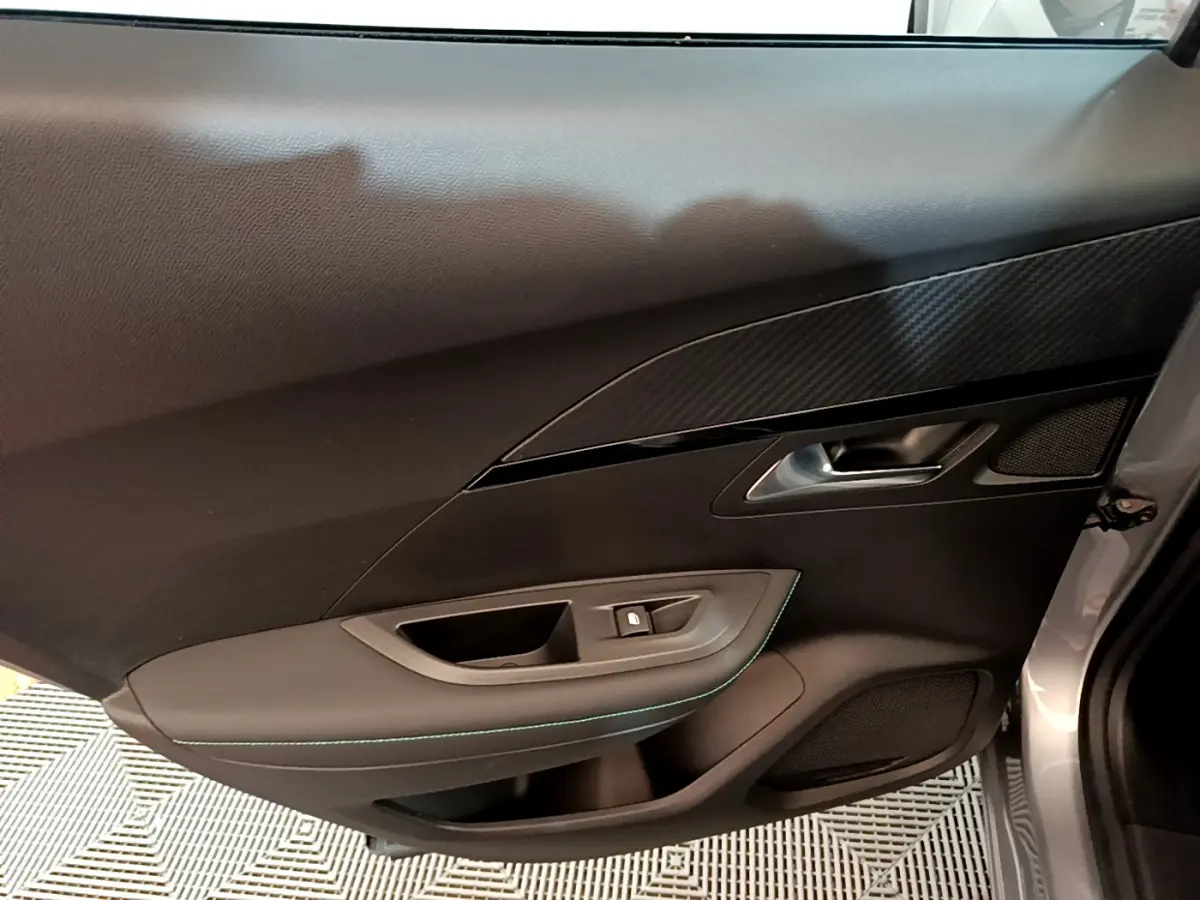 Vue rapprochée de la porte côté gauche gris clair du Peugeot 2008 avec garniture noire et surpiqûres vertes.