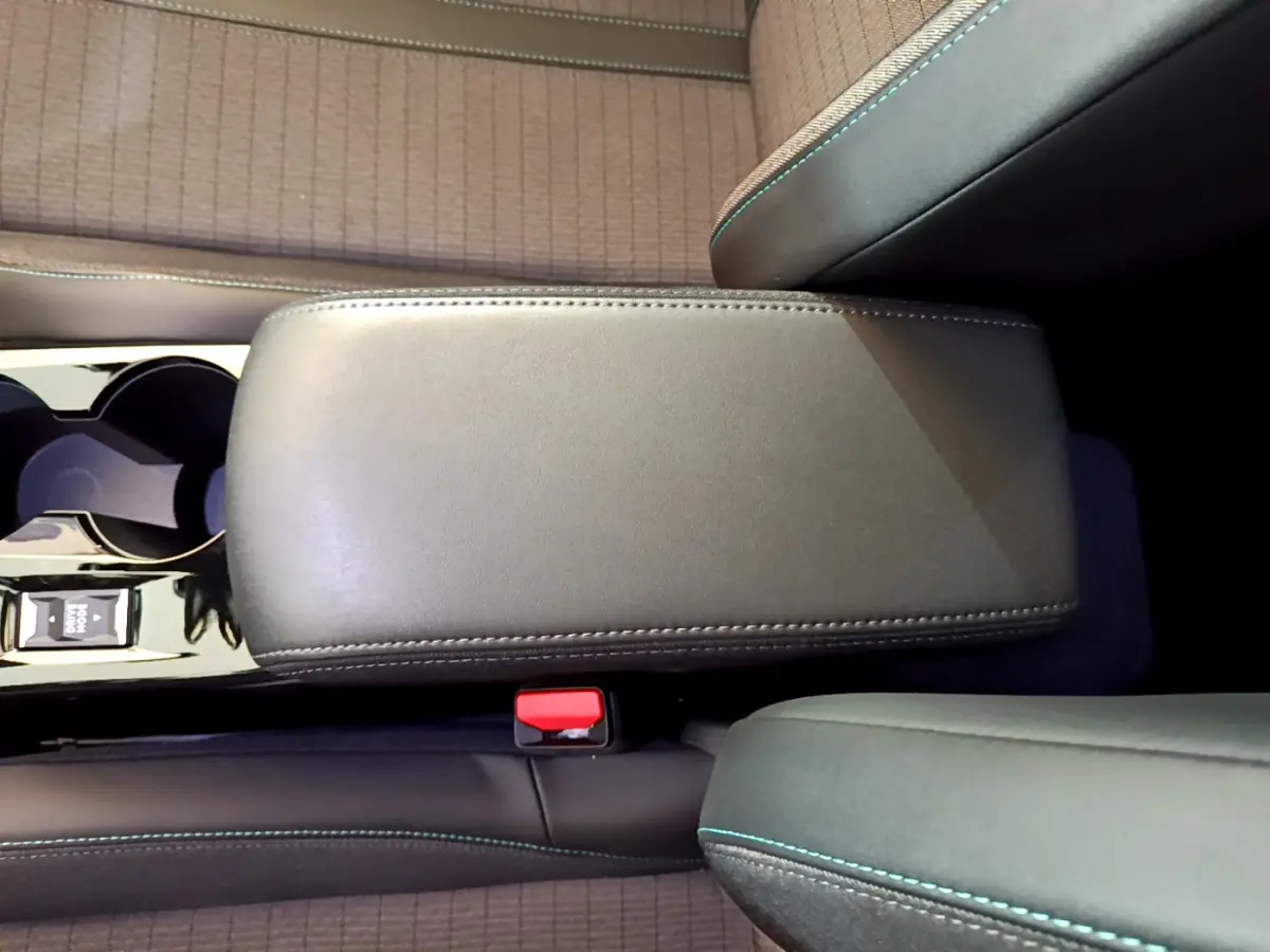 Vue rapprochée de l'accoudoir central noir et des sièges gris clair avec surpiqûres bleues du Peugeot 2008 2021.