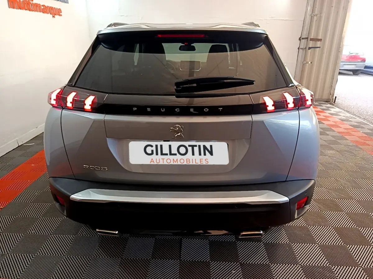 Vue arrière d'un Peugeot 2008 gris clair avec feux LED caractéristiques et logo au centre du hayon.
