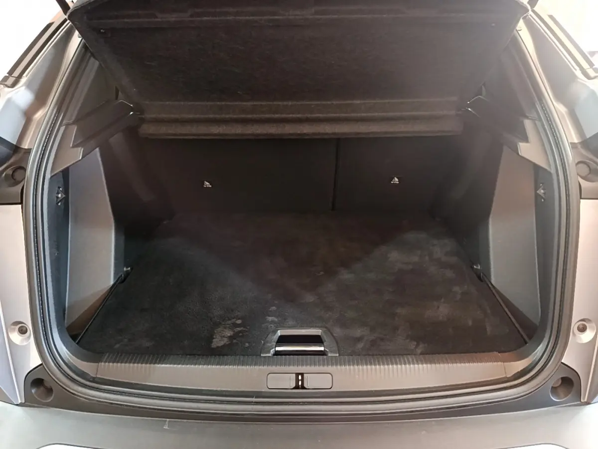 Coffre ouvert vu de l'arrière d'un Peugeot 2008 gris clair, espace de chargement propre et spacieux.