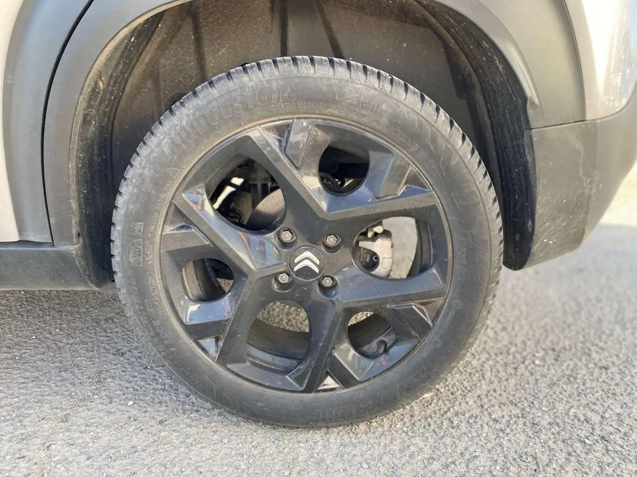 Gros plan sur la roue avant droite gris foncé d'un Citroën C3 Aircross 2024 avec jante noire et logo Citroën visible.