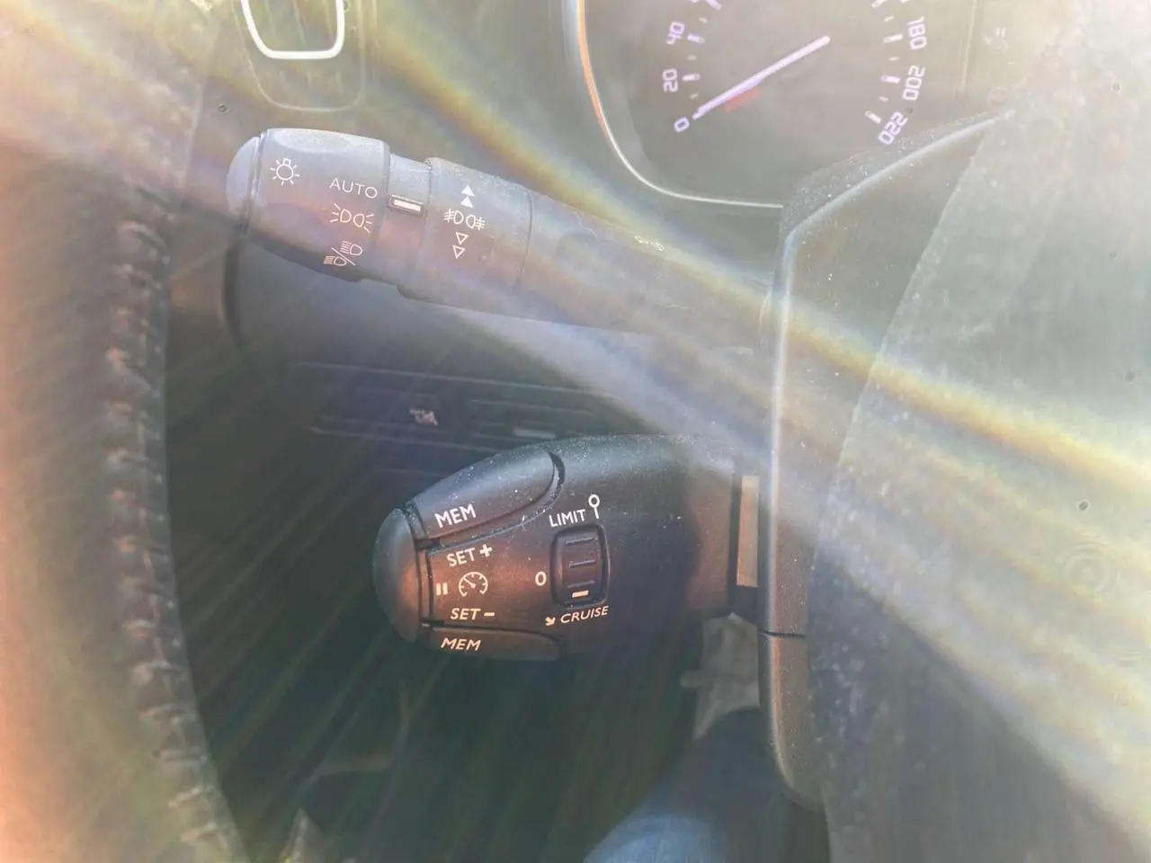 Gros plan sur les commandes au volant du Citroën C3 Aircross 2024 gris foncé, avec régulateur de vitesse et feux automatiques.