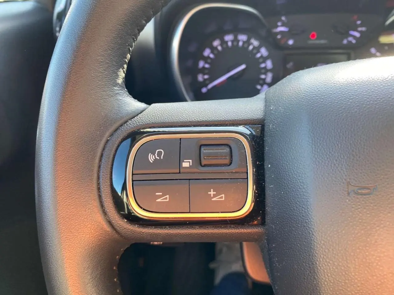 Gros plan sur la partie gauche du volant noir du Citroën C3 Aircross 2024 avec commandes audio intégrées.
