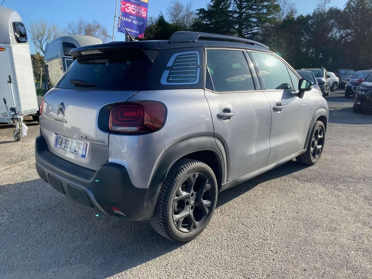 Vue 3/4 arrière droite d'un Citroën C3 Aircross gris foncé 2024 avec jantes noires et toit noir contrasté.