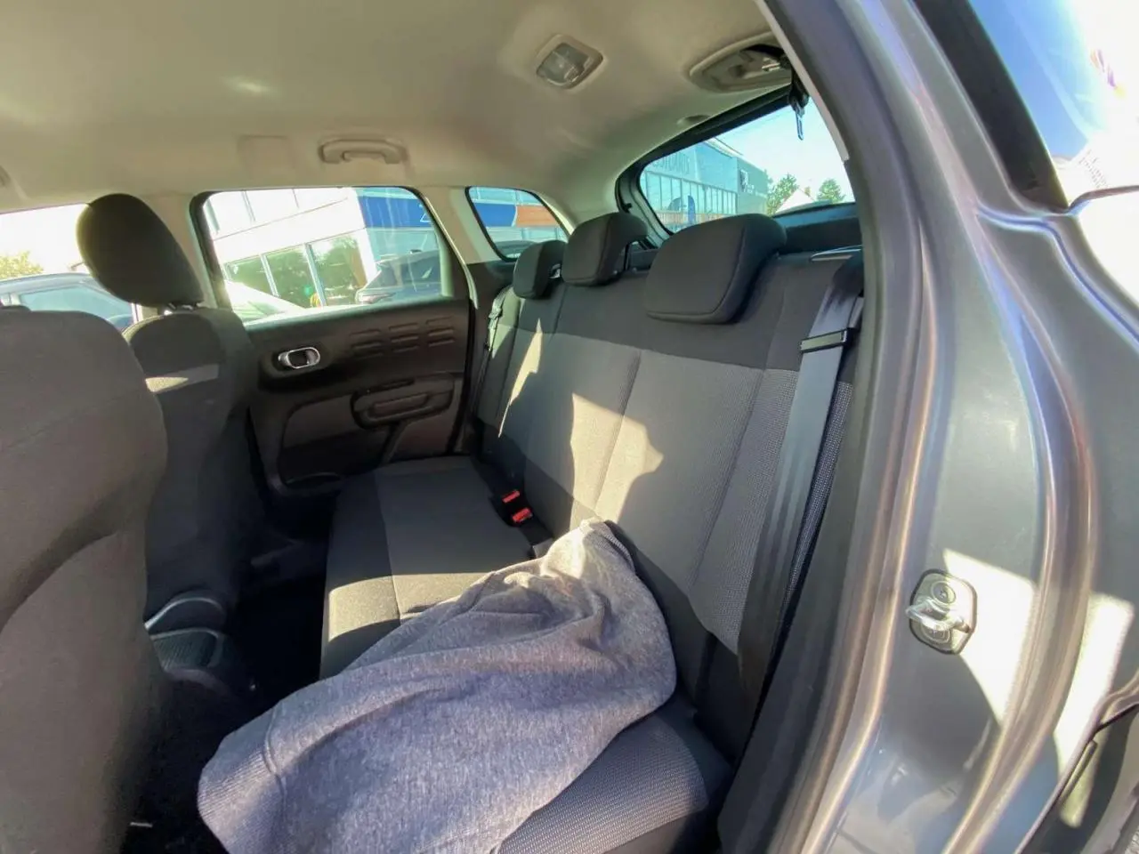 Vue intérieure arrière côté droit du Citroën C3 Aircross gris foncé 2024, montrant la banquette arrière et la portière ouverte.