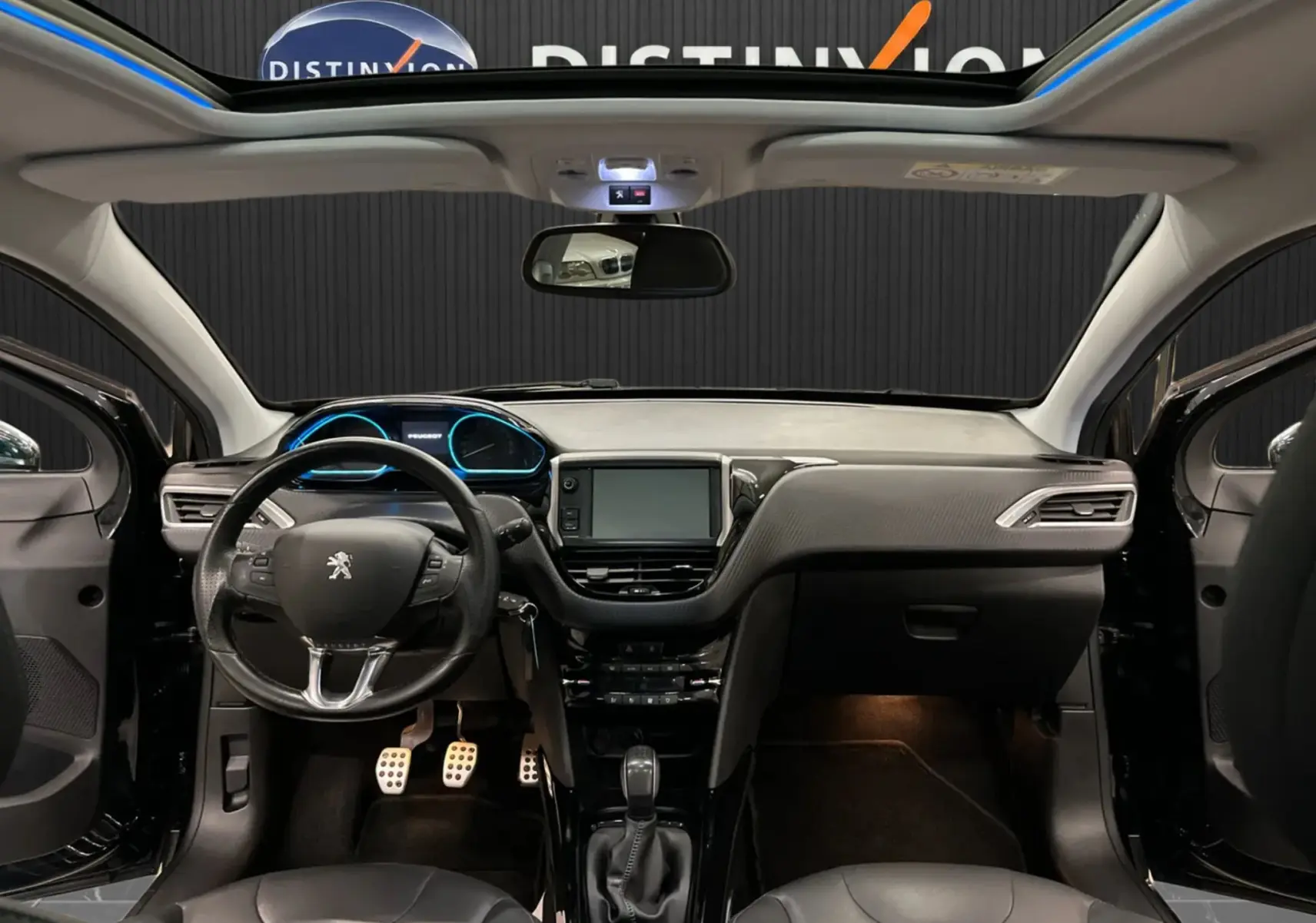 Vue intérieure avant du Peugeot 2008 noir 2018, mettant en valeur le tableau de bord moderne avec écran tactile et volant cuir.
