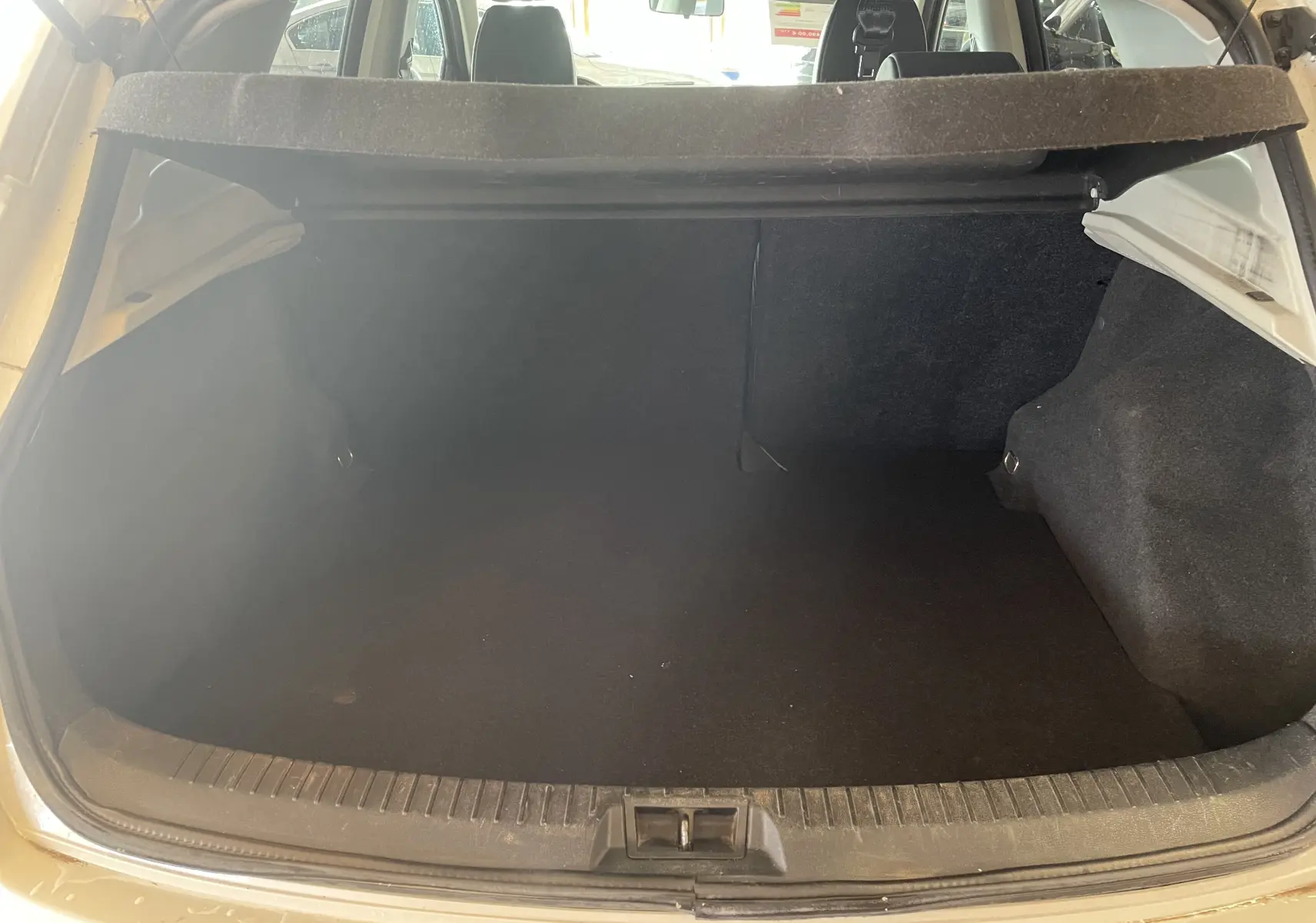 Coffre ouvert d'un Nissan Qashqai blanc 2013, vue arrière montrant l'espace de chargement vide et la plage arrière.