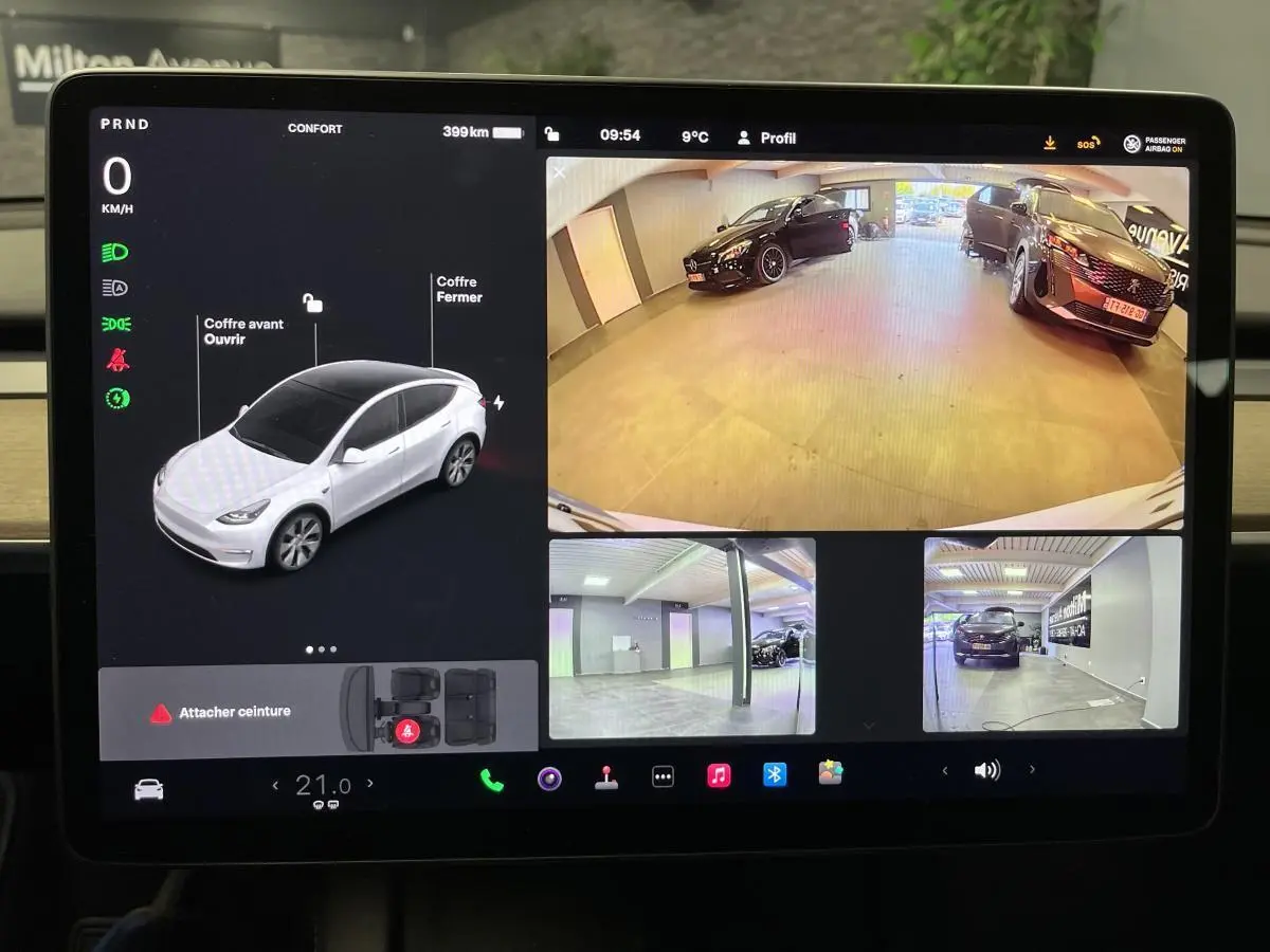 Écran tactile de Tesla Model Y blanc montrant la vue caméra 360° et l'état du véhicule en stationnement.