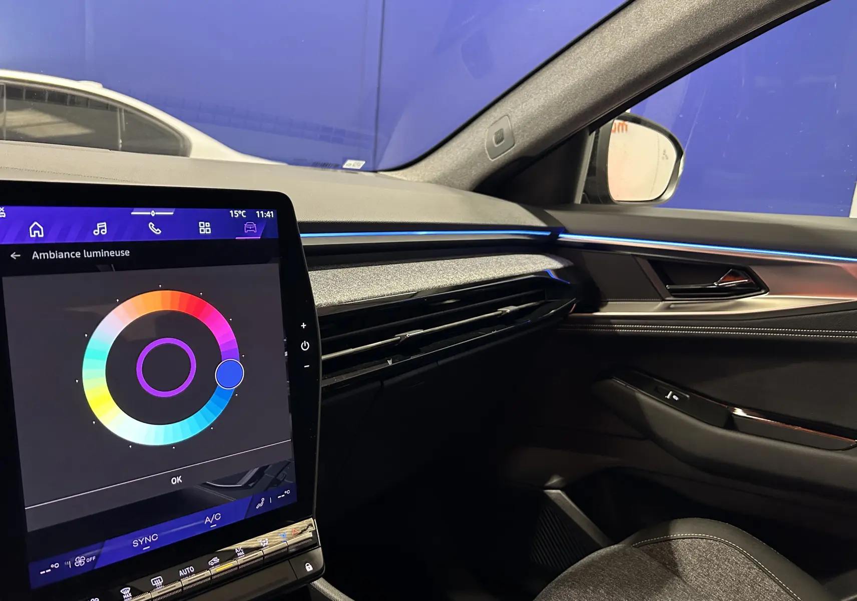 Intérieur côté passager du Renault Austral Ph.2 noir étoilé, avec écran tactile et éclairage d'ambiance bleu sur la planche de bord.