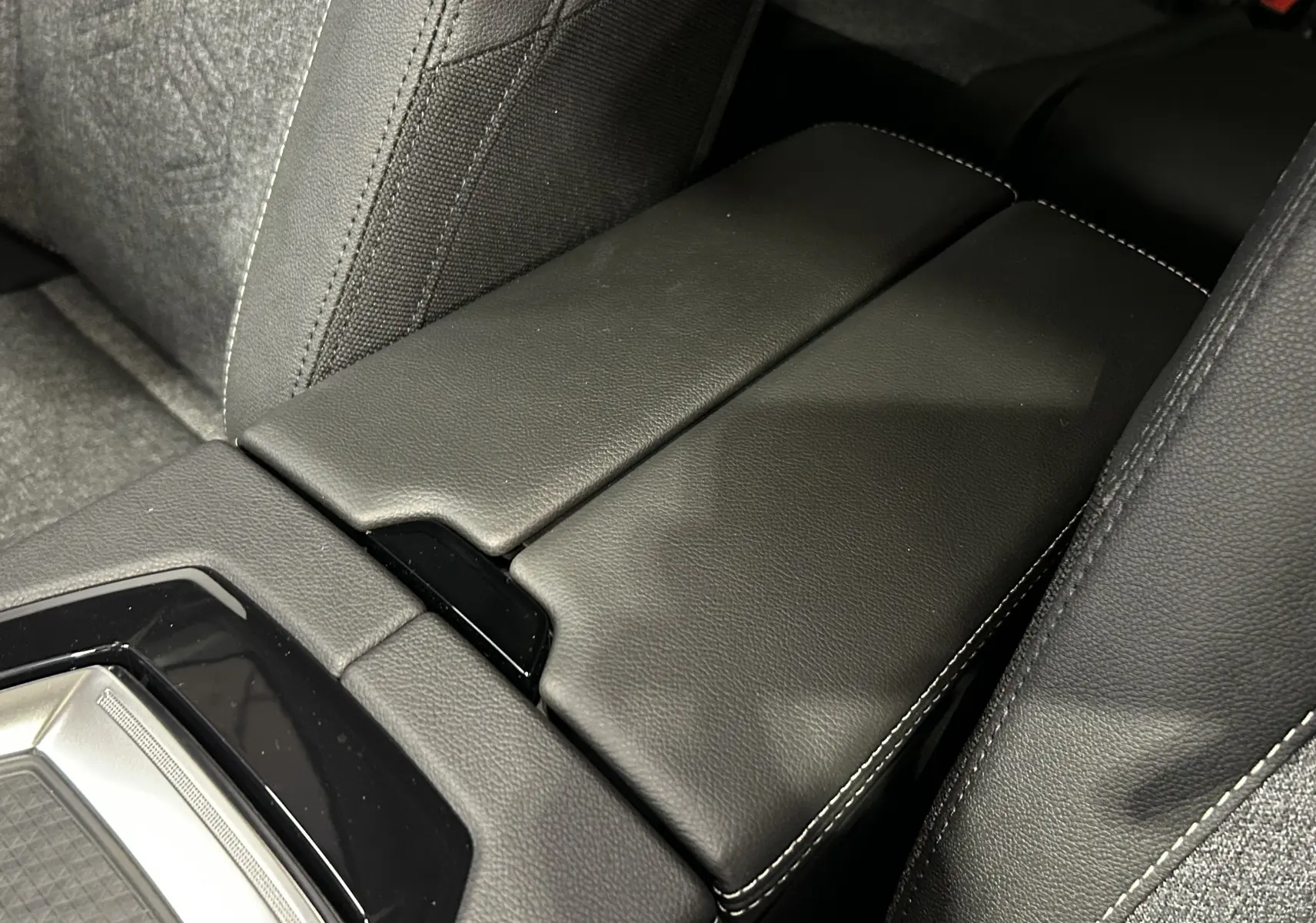 Gros plan sur l'accoudoir central en cuir noir avec surpiqûres blanches du Renault Austral Ph.2 E-TECH 2025.