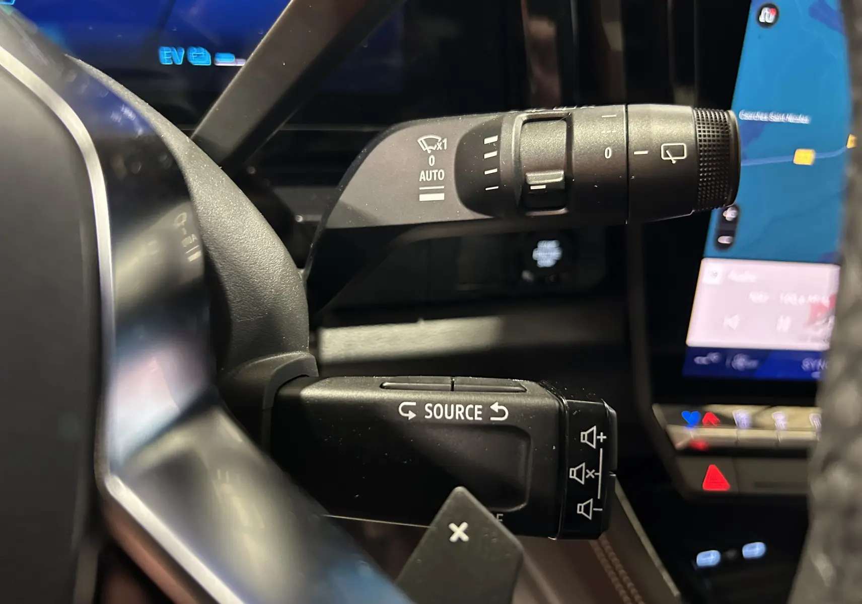Gros plan sur les commandes au volant du Renault Austral Ph.2 E-TECH noir étoilé, avec écran tactile en arrière-plan.