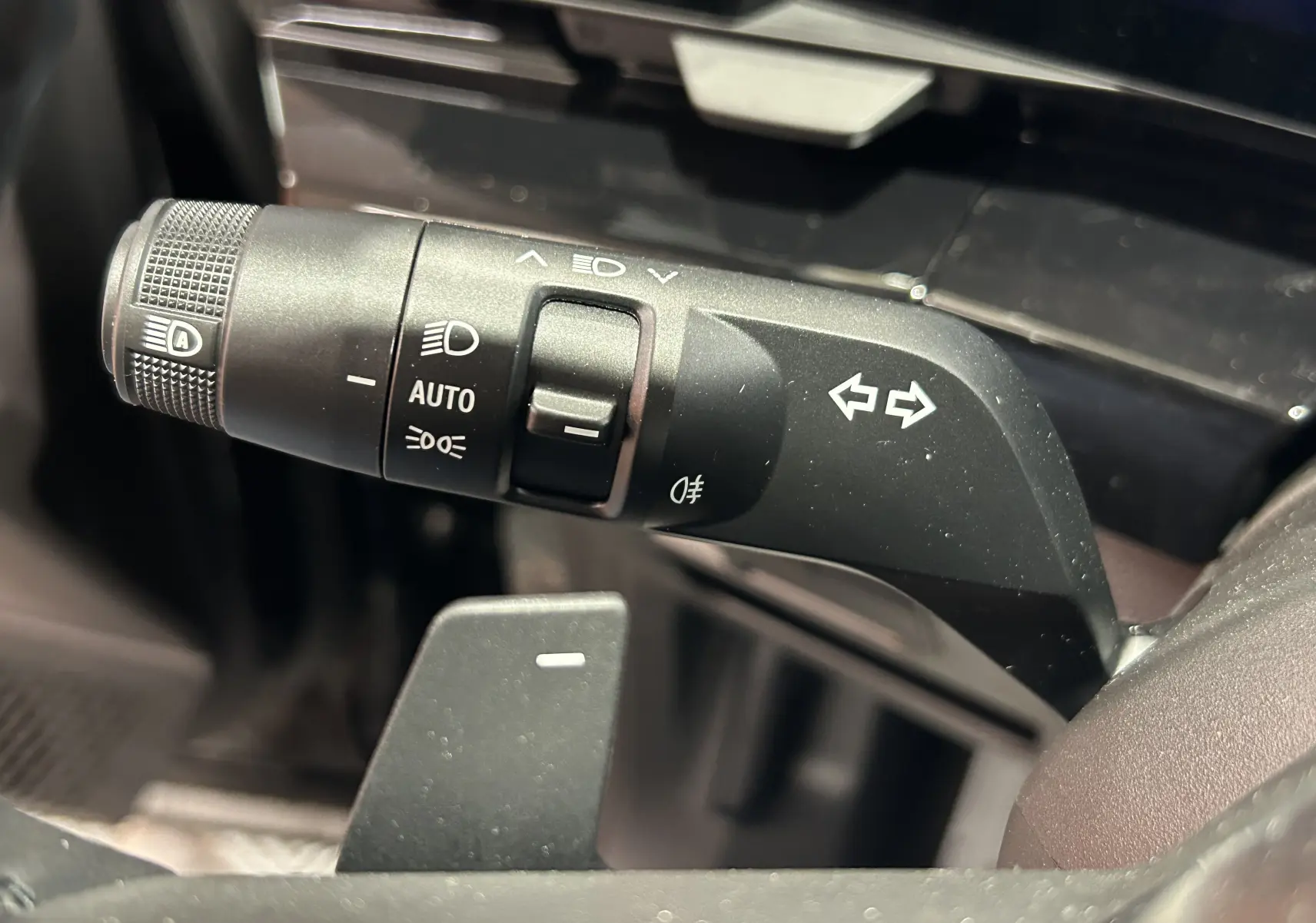 Gros plan sur la commande des clignotants et feux automatiques du volant du Renault Austral Ph.2 noir étoilé.