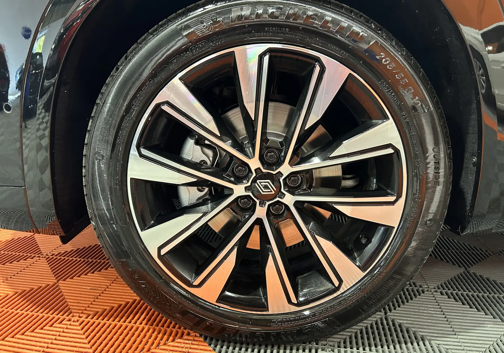 Gros plan sur la jante alliage bicolore du Renault Austral noir étoilé, mettant en valeur le logo central et le pneu Michelin.