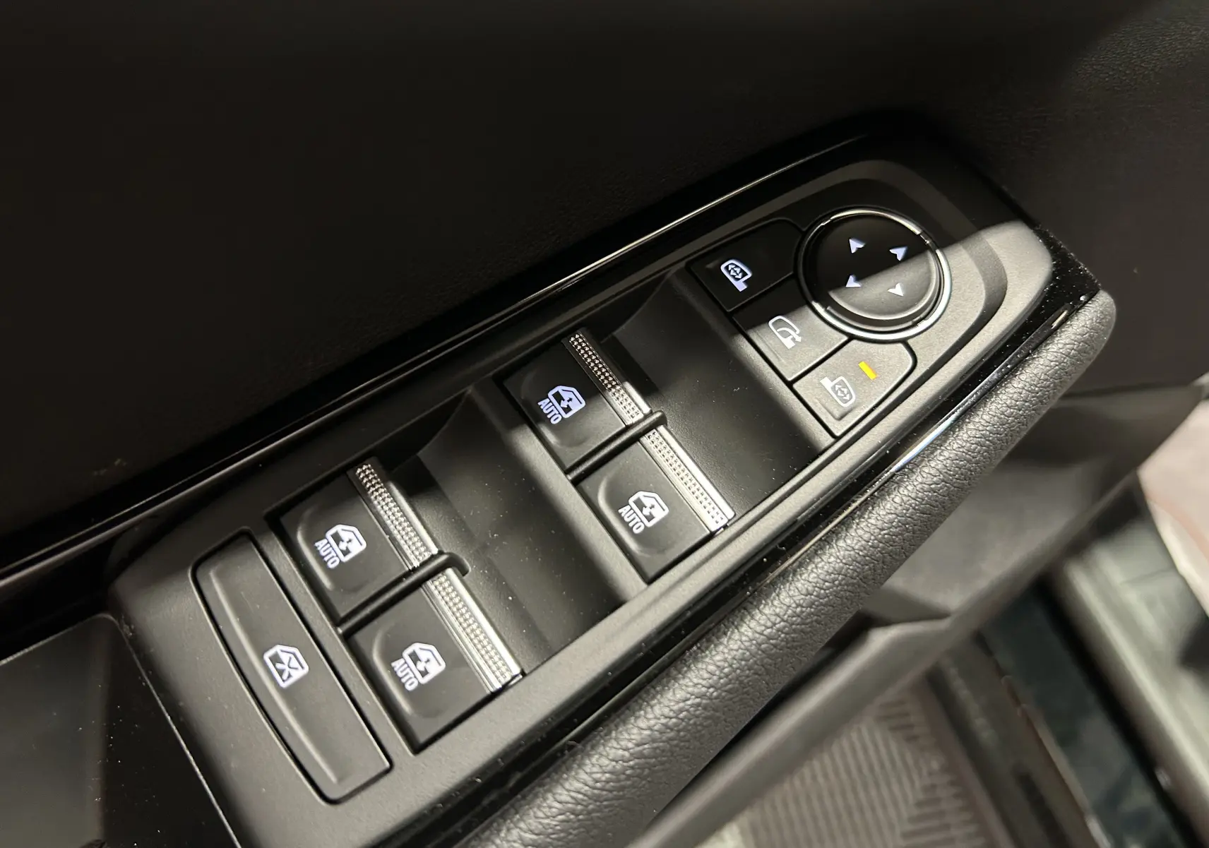 Gros plan sur les commandes de lève-vitres et rétroviseurs côté gauche d'un Renault Austral noir étoilé 2025.