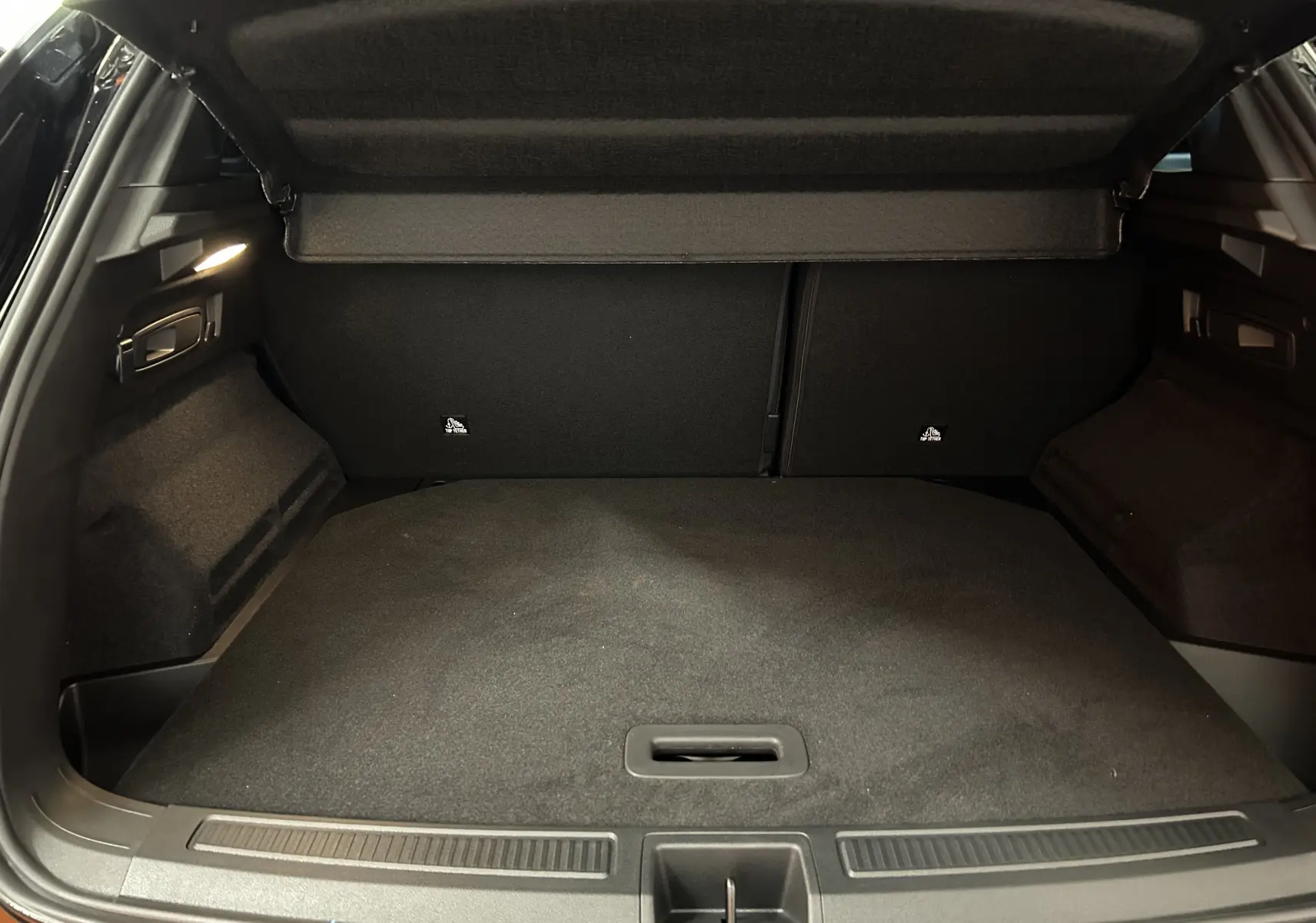 Coffre ouvert du Renault Austral Ph.2 E-TECH noir étoilé, vue intérieure arrière avec hayon électrique relevé.