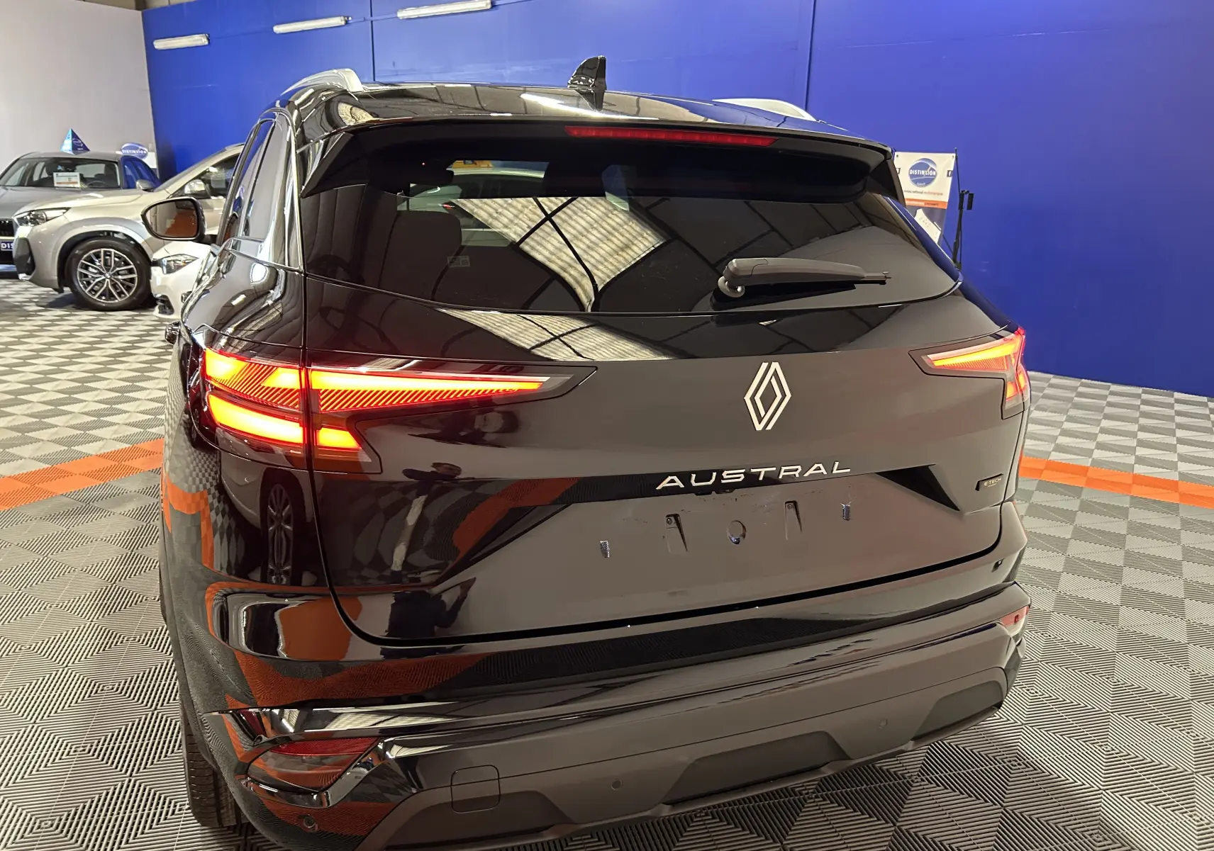 Vue arrière d'un Renault Austral noir étoilé avec feux LED allumés dans un showroom intérieur.