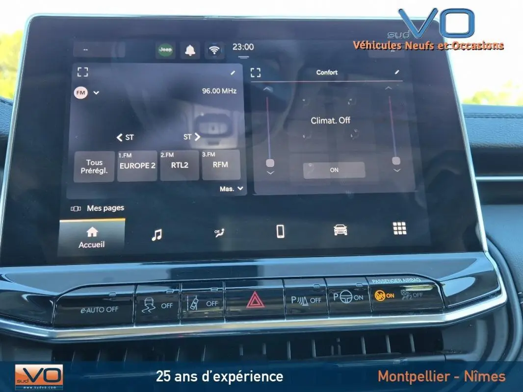 Écran tactile central du Jeep Compass gris 2024 montrant radio FM et commandes climatisation dans l'habitacle.