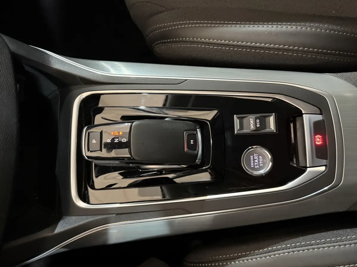 Vue rapprochée de la console centrale de la Peugeot 308 noire, avec levier de boîte auto, bouton start/stop et sélecteur mode sport/eco.