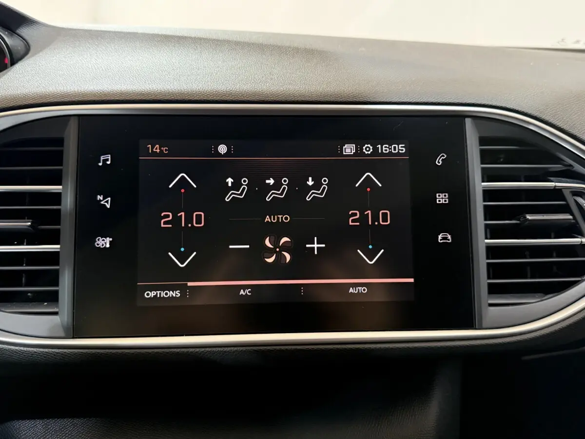Écran tactile central affichant la climatisation à 21°C sur Peugeot 308 noir, vue frontale du tableau de bord.