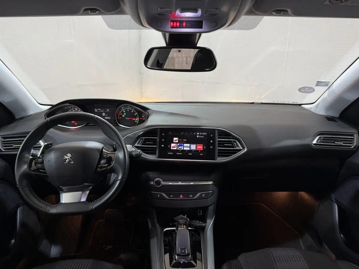 Intérieur noir de la Peugeot 308 2020, vue frontale du tableau de bord avec écran tactile et volant multifonctions cuir.