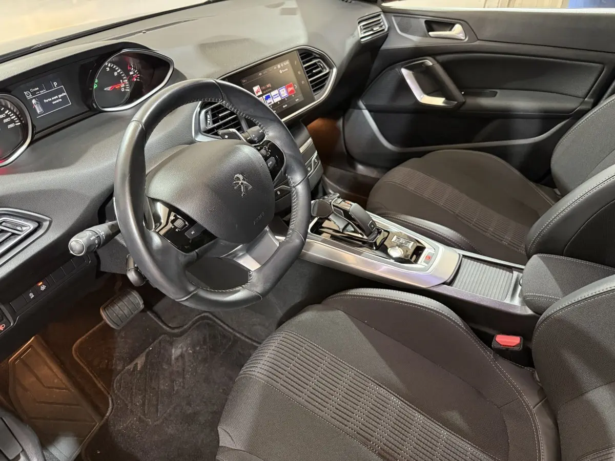 Intérieur noir de la Peugeot 308 Puretech 130 S&S EAT8 Allure, vue côté conducteur sur le tableau de bord et la console centrale.