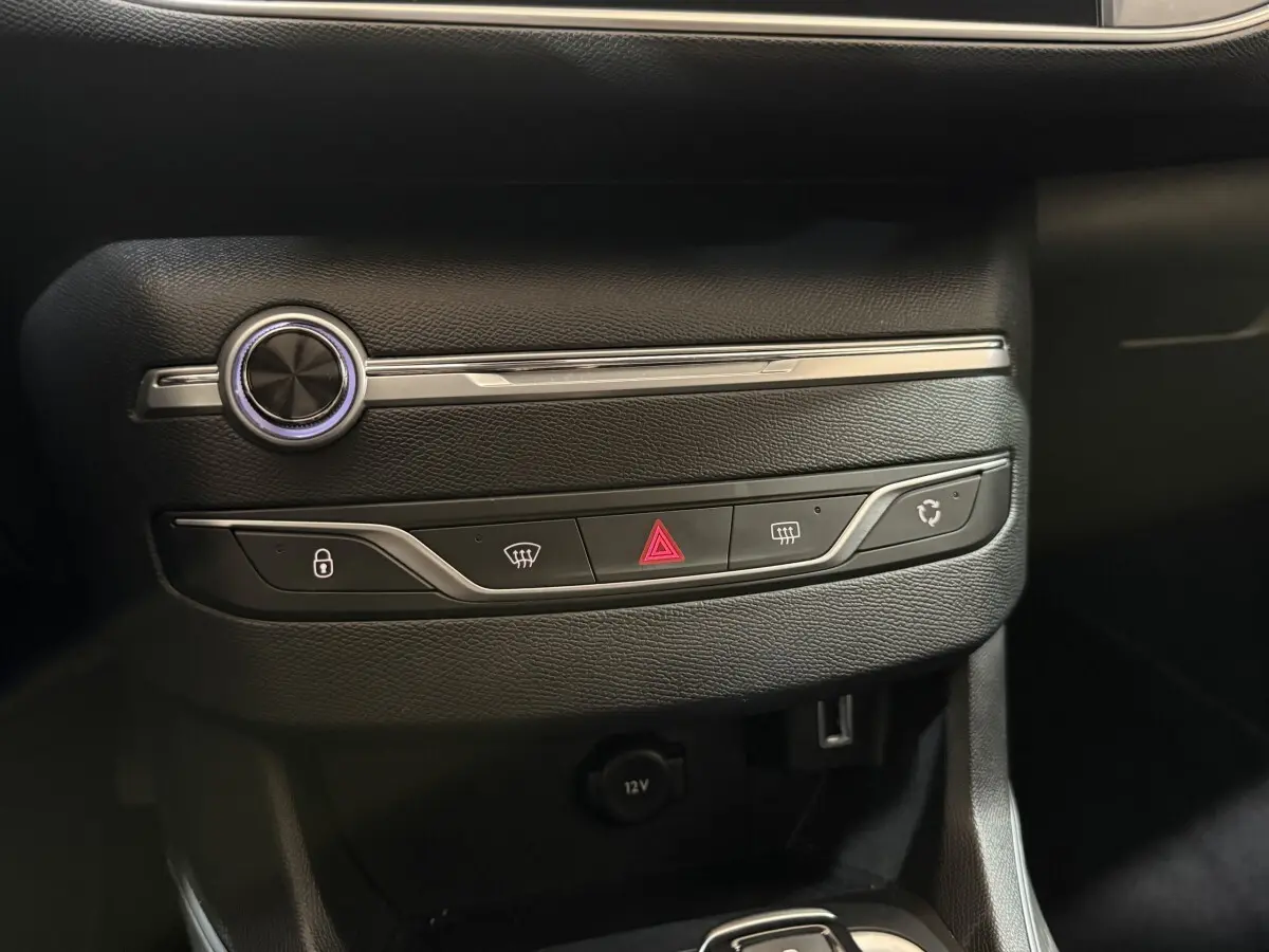 Gros plan sur la console centrale noire de la Peugeot 308 Puretech 130, avec boutons de verrouillage et hazard visibles.