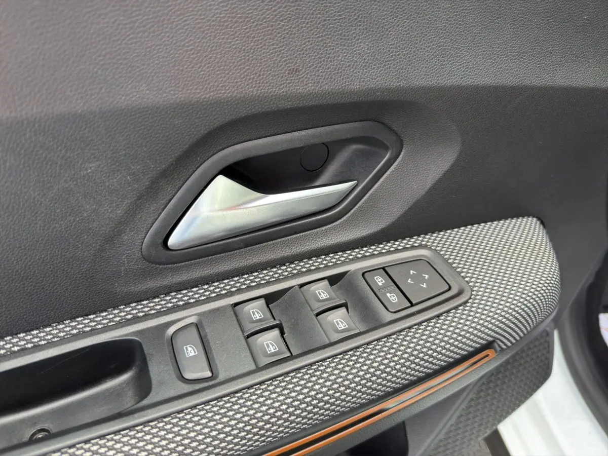 Détail de la porte côté conducteur de la Dacia Sandero Stepway blanche, avec commandes des vitres et poignée intérieure.