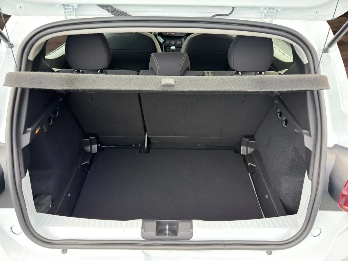 Vue du coffre ouvert d'une Dacia Sandero Stepway blanche, montrant l'espace de chargement et la banquette arrière noire.