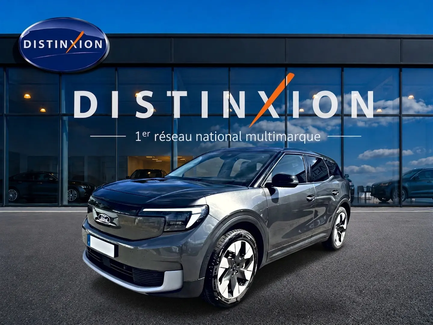 Ford Explorer électrique gris en vue 3/4 avant droit devant une vitrine avec logo Distinxion.