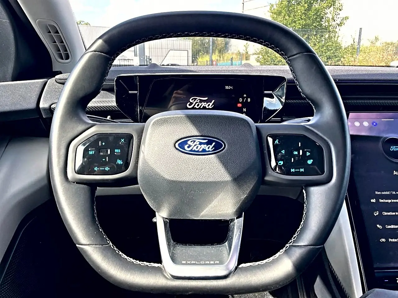 Vue rapprochée du volant noir du Ford Explorer 2025 avec commandes tactiles et logo Ford central visible.
