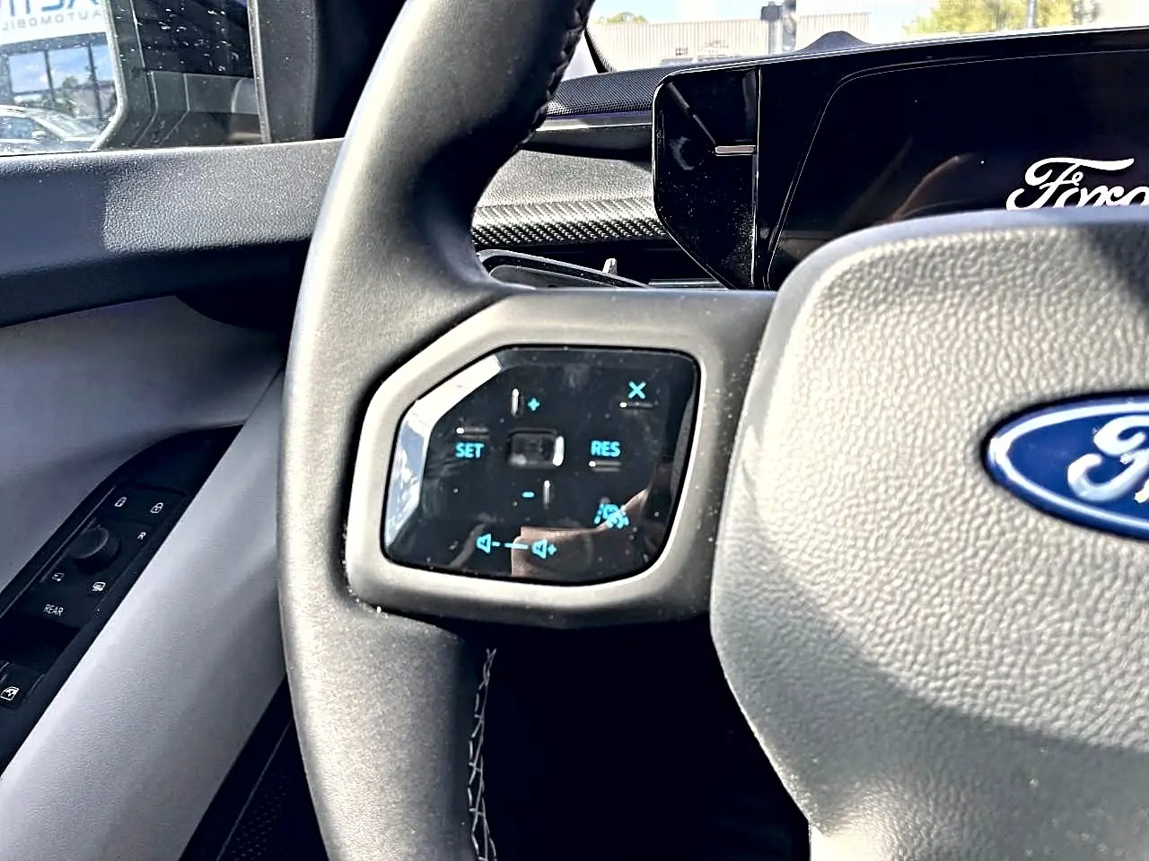 Gros plan sur le volant gris du Ford Explorer 2025 avec commandes multifonctions et logo Ford visible.