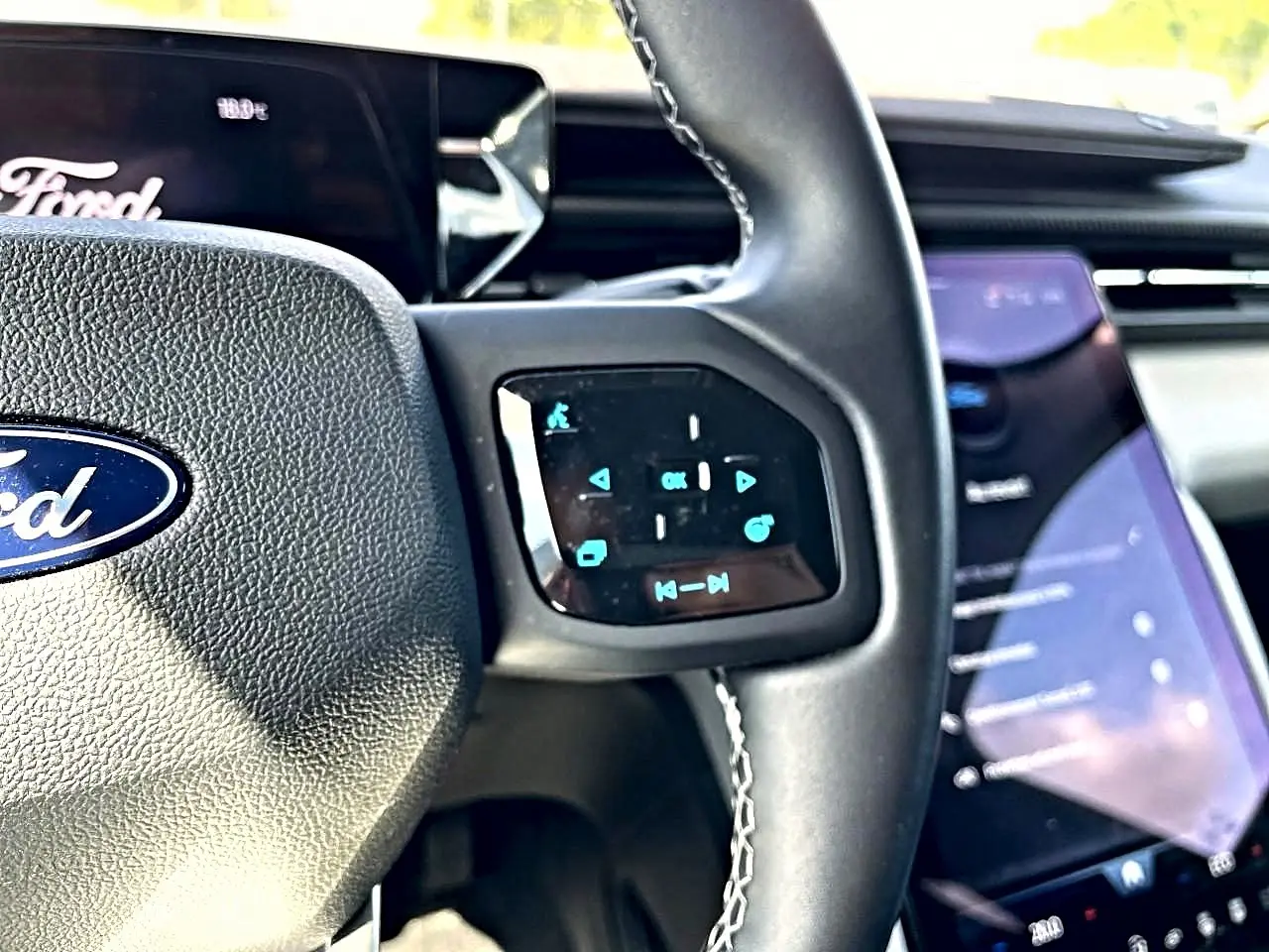Gros plan sur le volant multifonction noir et l’écran tactile vertical du tableau de bord du Ford Explorer gris.