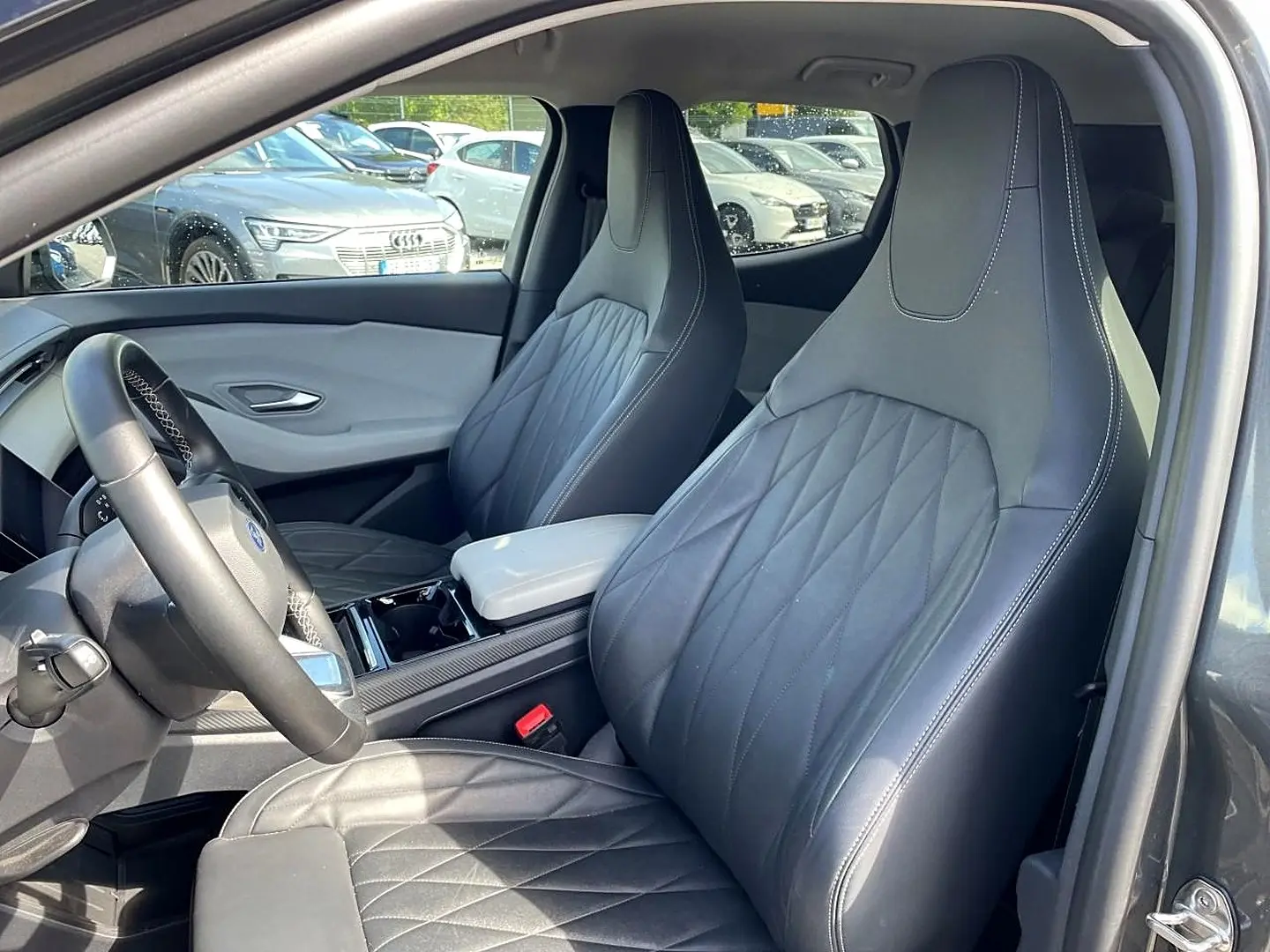 Vue intérieure côté conducteur du Ford Explorer gris 2025, mettant en valeur les sièges sport en cuir noir et l'accoudoir central.
