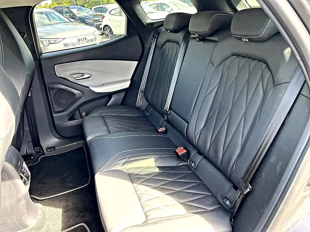 Vue côté droit de la banquette arrière en cuir noir matelassé du Ford Explorer gris, avec ceinture de sécurité et porte bicolore.