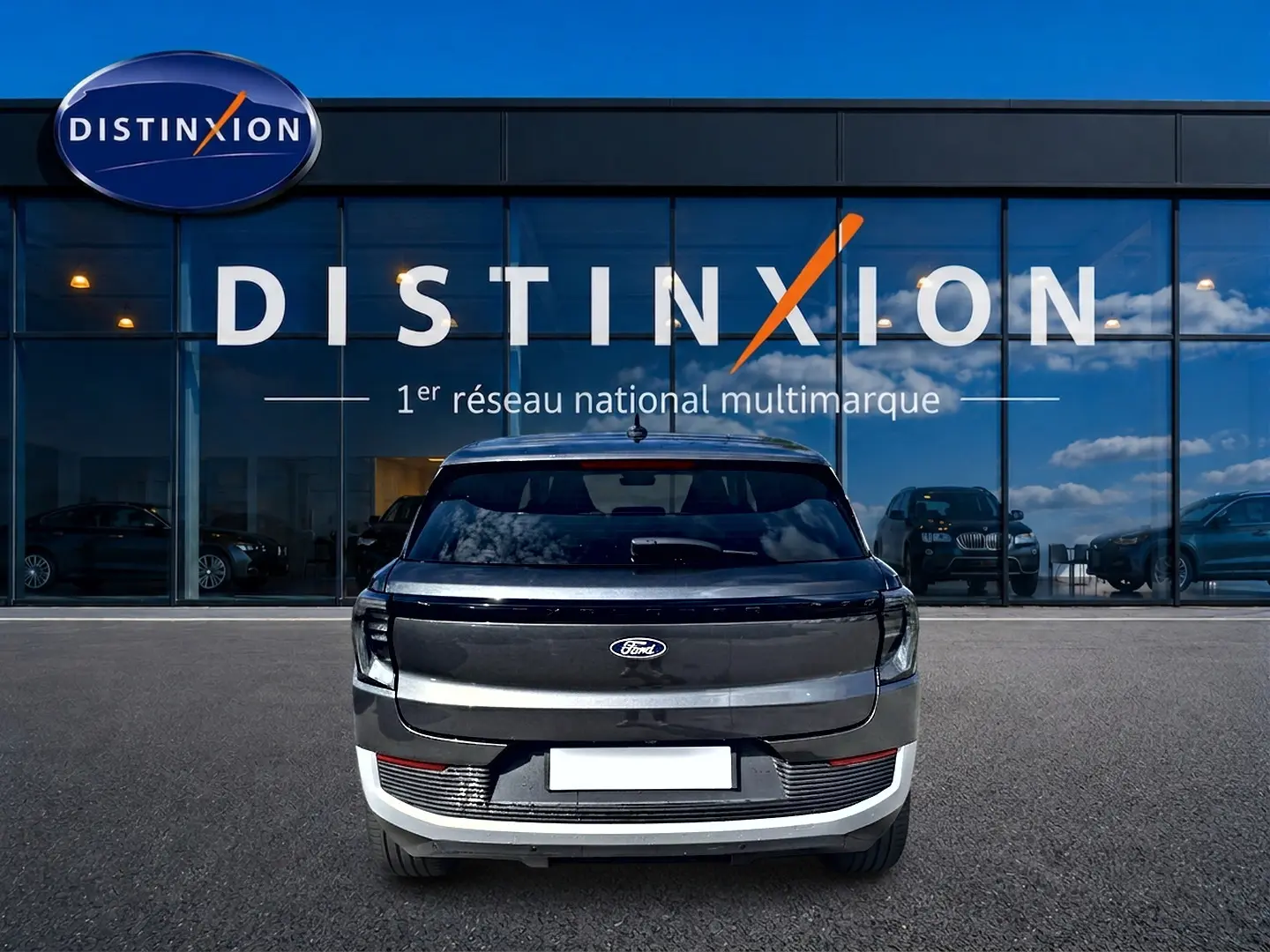 Vue arrière d'un Ford Explorer gris électrique 2025 garé devant une vitrine avec logo Distinxion.