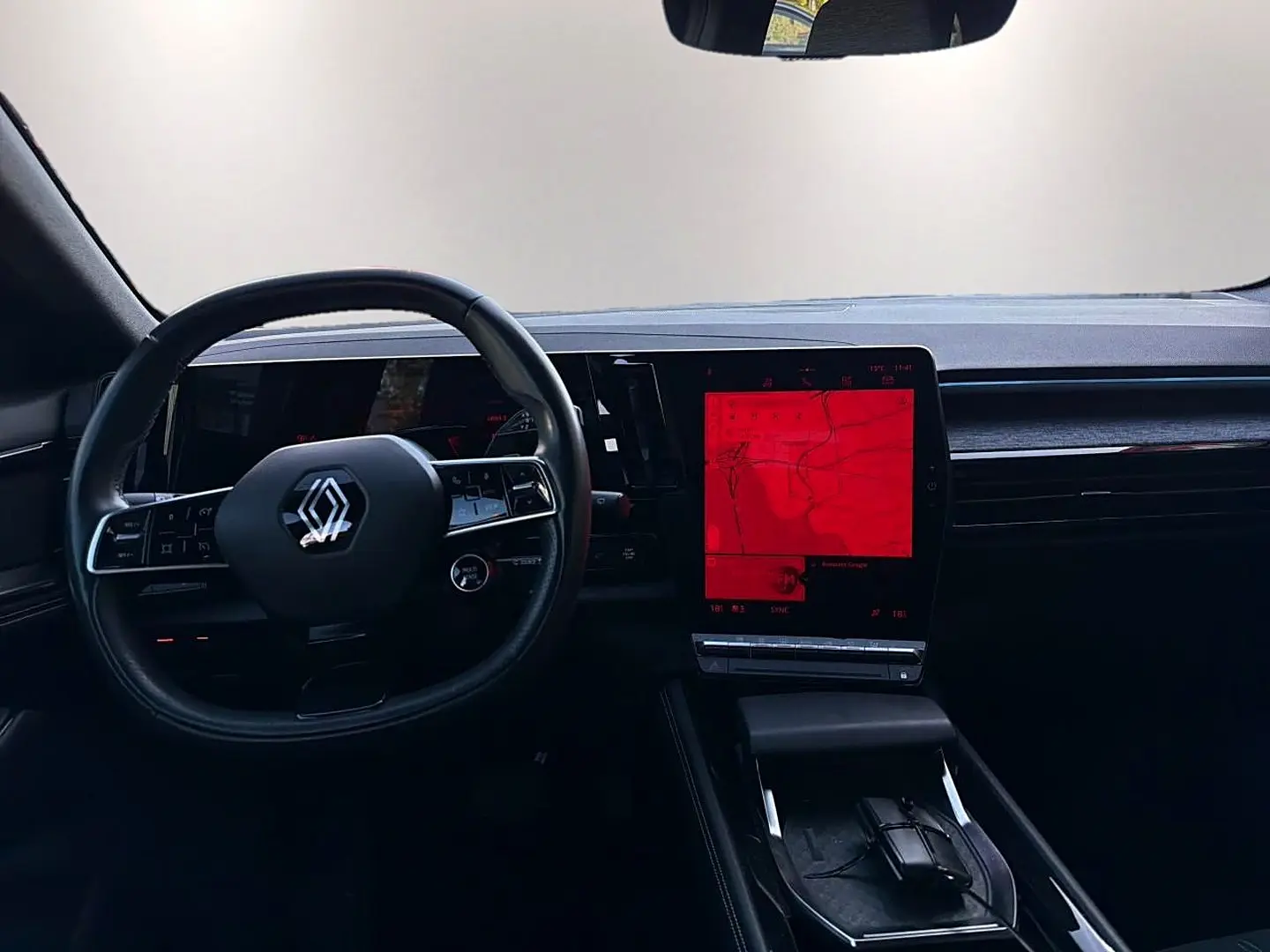 Vue intérieure du tableau de bord noir du Renault Austral 2023 avec volant cuir multifonction et écran tactile central vertical.