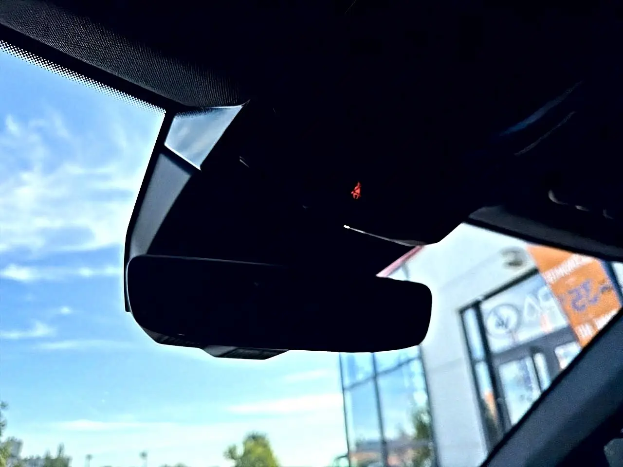 Gros plan sur le rétroviseur intérieur noir du Renault Austral 2023, avec ciel bleu visible par le pare-brise.
