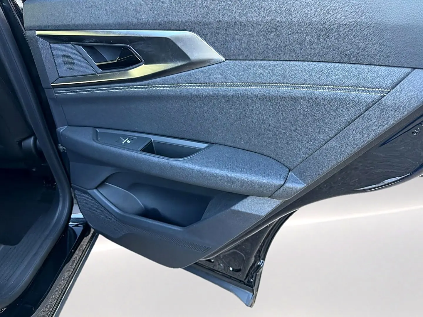 Vue rapprochée de la porte arrière gauche noire du Renault Austral 2023 avec garniture tissu et plastique noir.