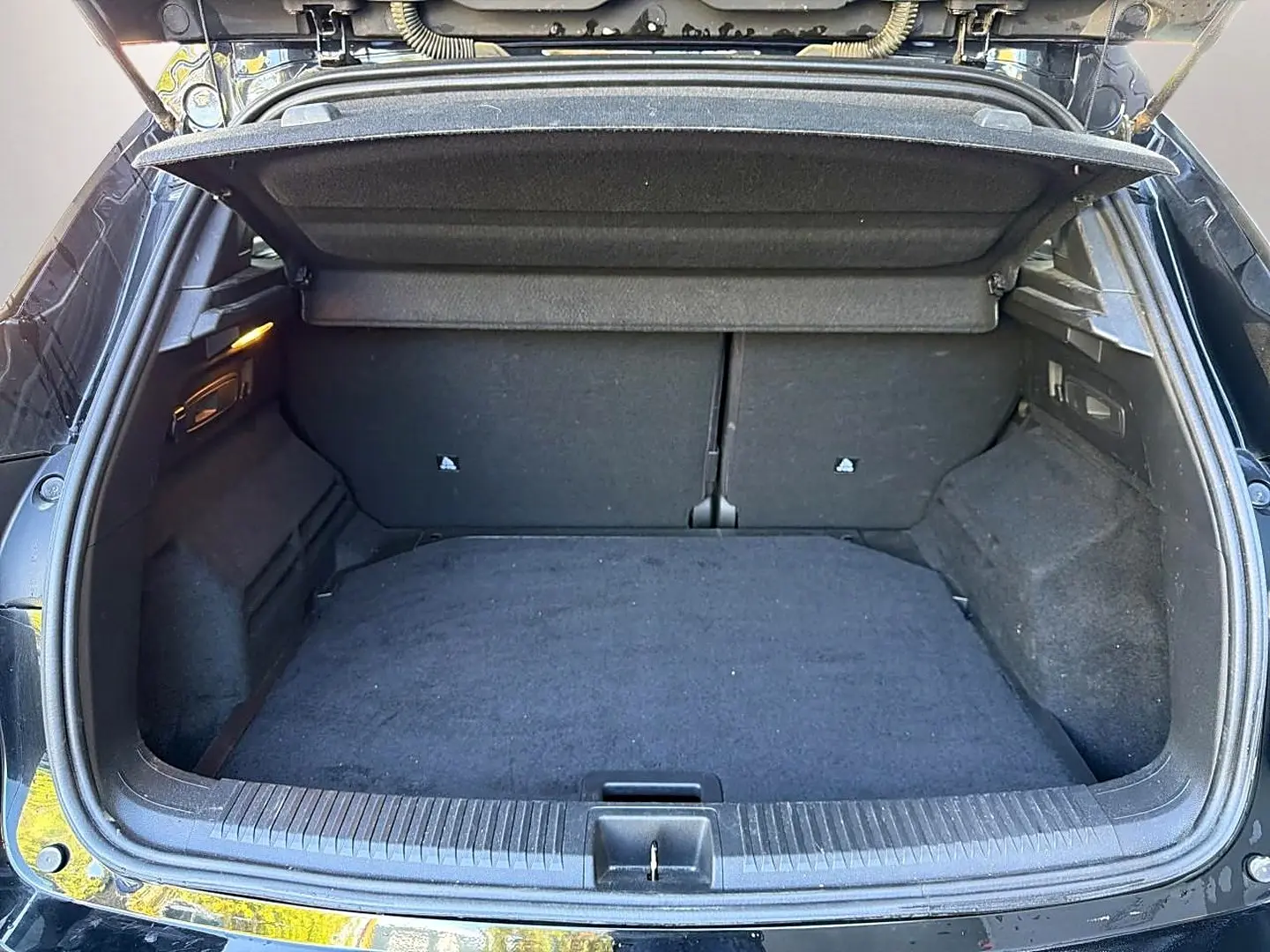 Coffre ouvert vu de l'arrière d'un Renault Austral noir, montrant un espace de chargement vide et tapis noir.