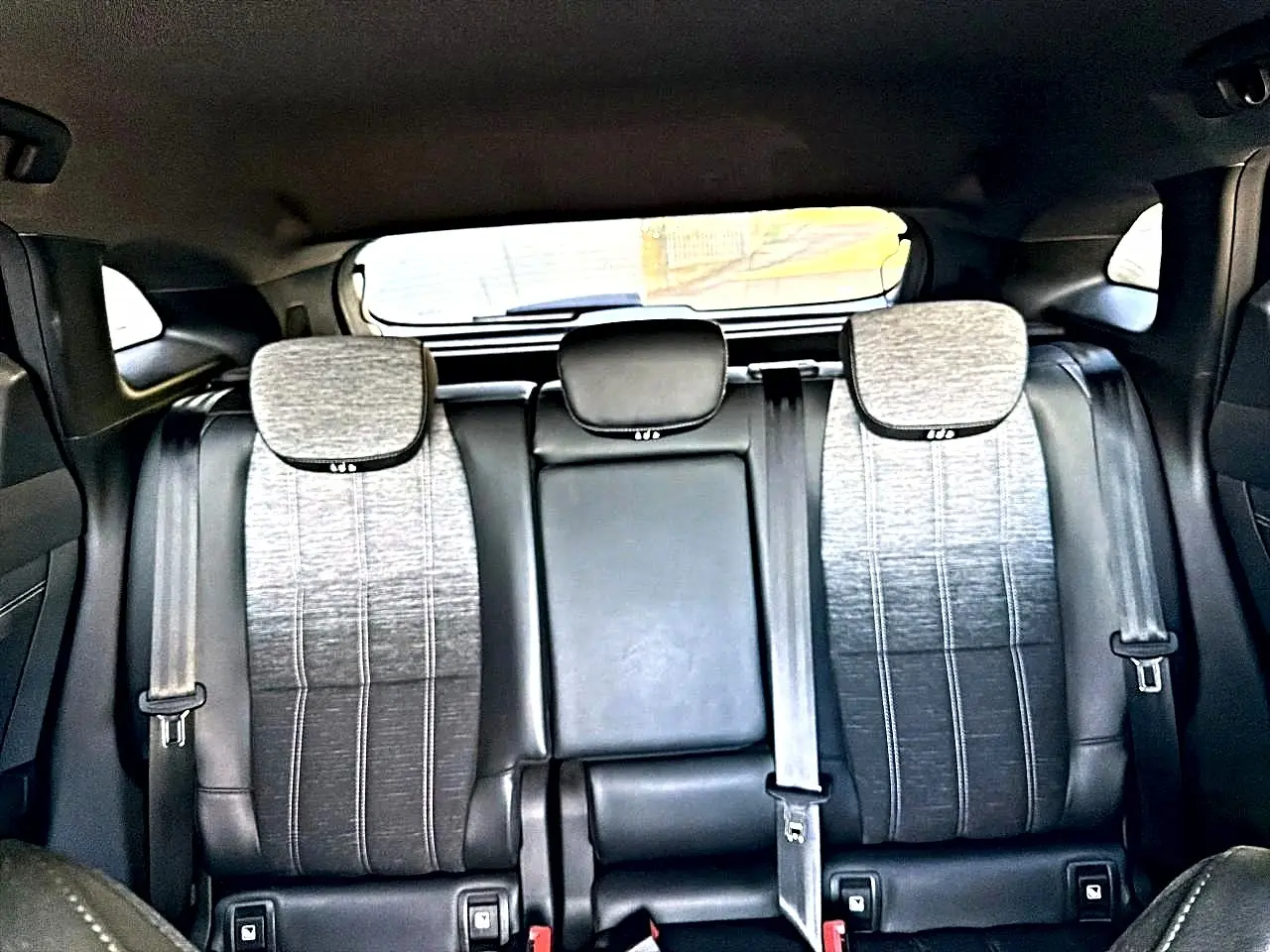 Vue arrière intérieure montrant la banquette arrière gris dégradé avec appuie-têtes et ceintures de sécurité du Renault Austral noir.