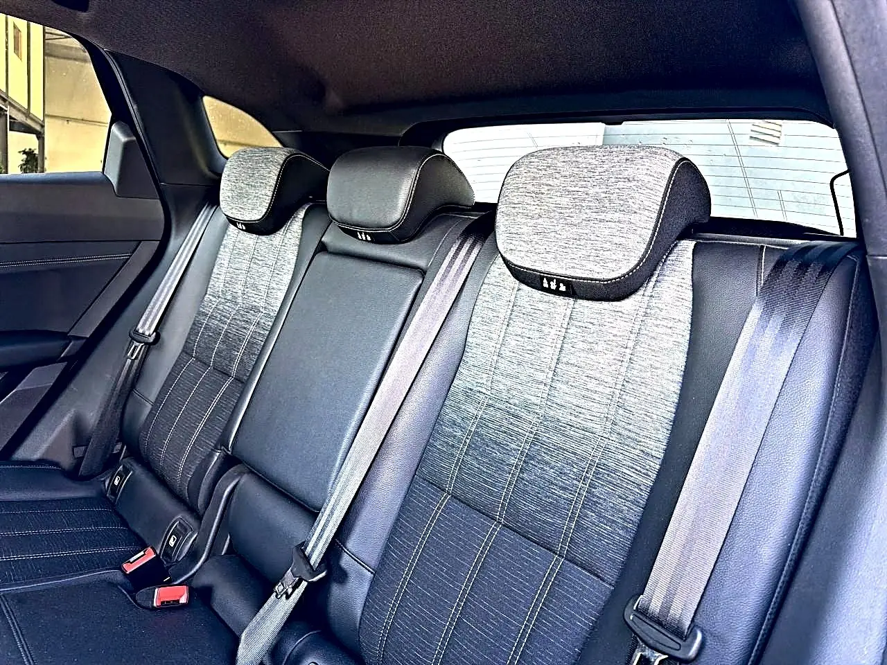 Vue intérieure arrière montrant la banquette gris dégradé avec appuie-têtes et ceintures de sécurité du Renault Austral noir.
