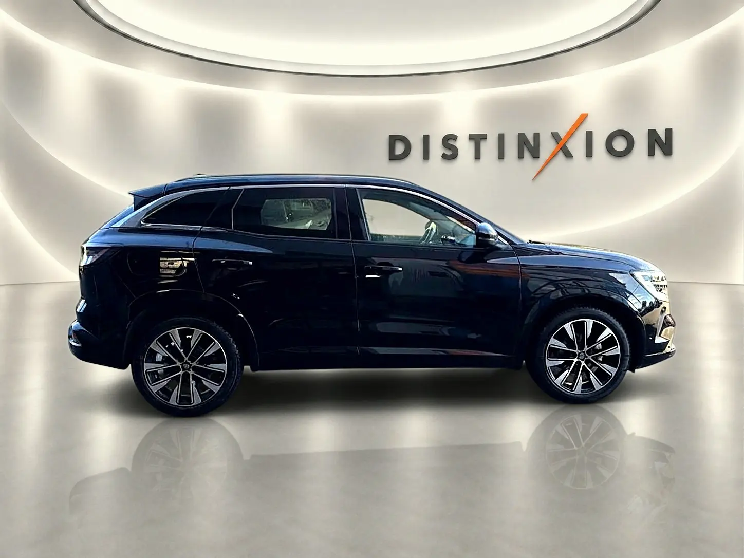 Profil droit d'un Renault Austral noir 2023 avec jantes alu, posé devant un mur blanc éclairé et le logo Distinxion.