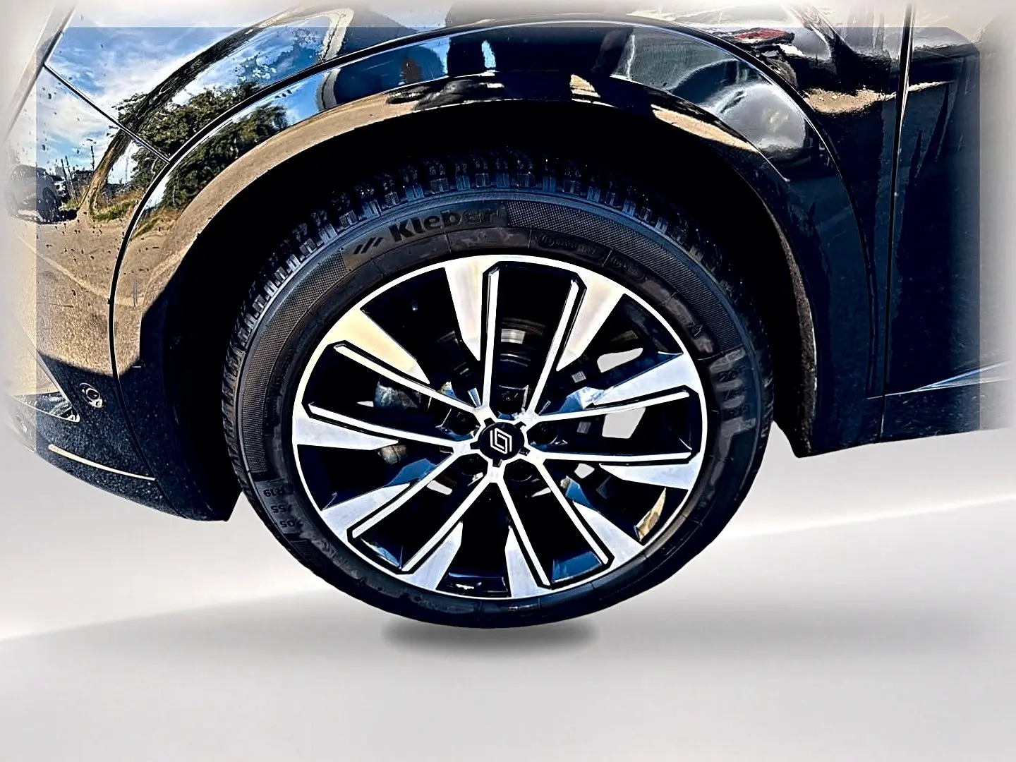 Gros plan sur la roue avant droite noire du Renault Austral 2023 avec jante alu bicolore et carrosserie noire brillante.