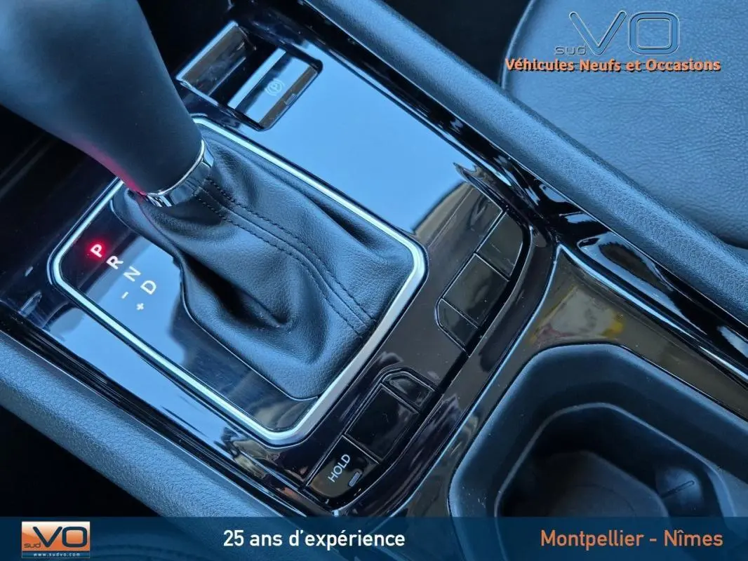 Gros plan sur la console centrale noire du Jeep Compass 2024 avec levier de vitesse automatique et accoudoir gris.