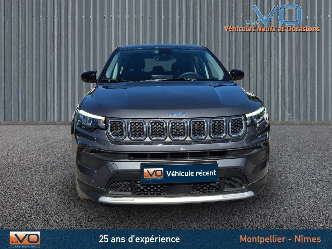 Vue frontale d'un Jeep Compass gris 2024 avec calandre à sept fentes et phares LED allumés.