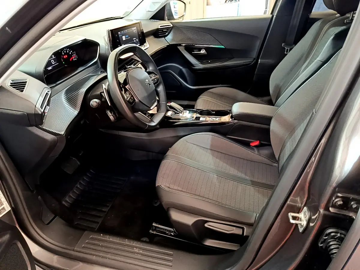 Intérieur avant droit du Peugeot 2008 gris foncé, montrant sièges tissu, volant multifonctions et tableau de bord digital.