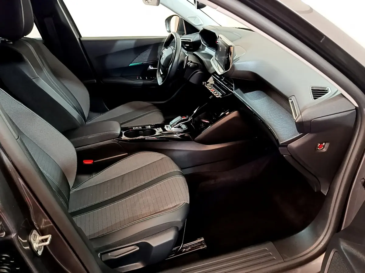 Intérieur vue côté passager du Peugeot 2008 gris foncé, avec tableau de bord moderne et sièges tissu noirs.